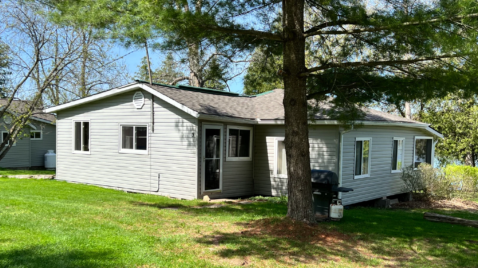 Pigeon Lake Resort Cottage three exterior front entrance with yard and trees.